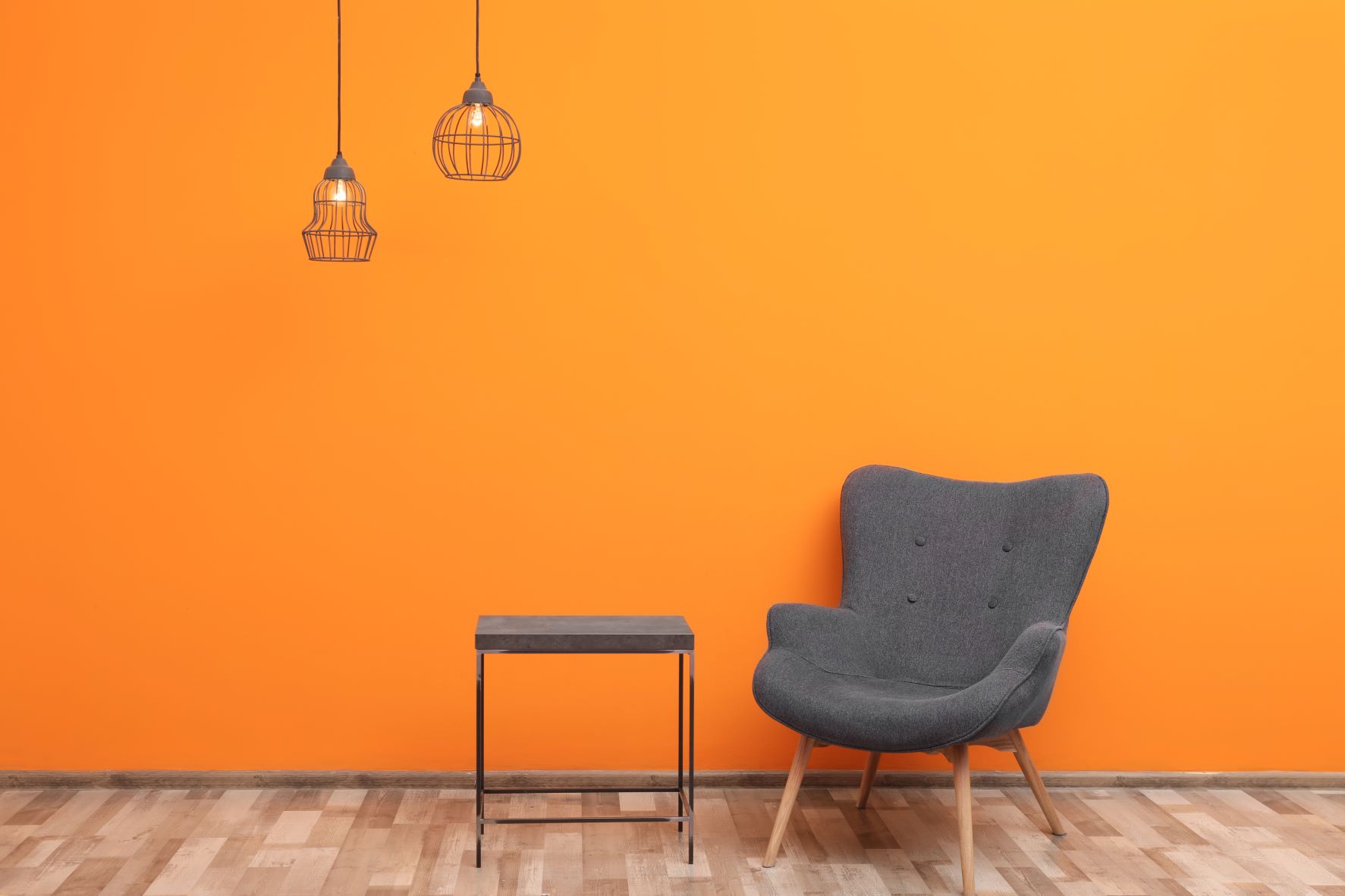 bequemer Sessel und kleines Tischchen vor einer orangen Wand