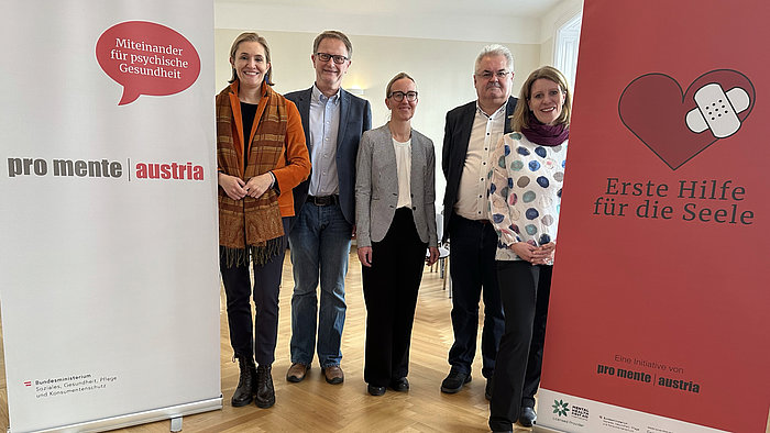 Es zeigt drei weibliche und zwei Männliche Personen. Links und rechts davon jeweils ein großer Aufsteller für Pro Mente Austria und Erste Hilfe für die Seele.
