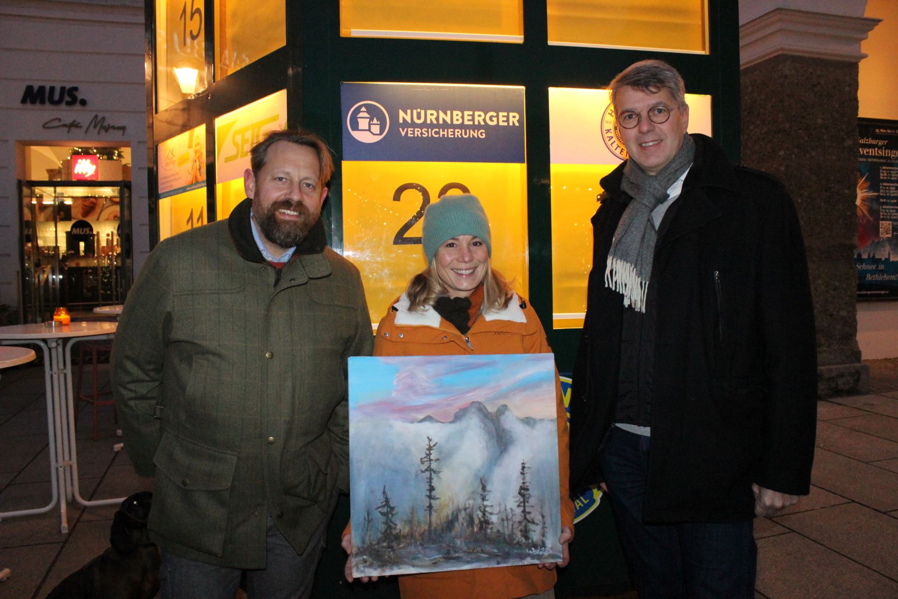 Eine Dame hält steht zwischen 2 Herren und hält ein Bild in der Hand