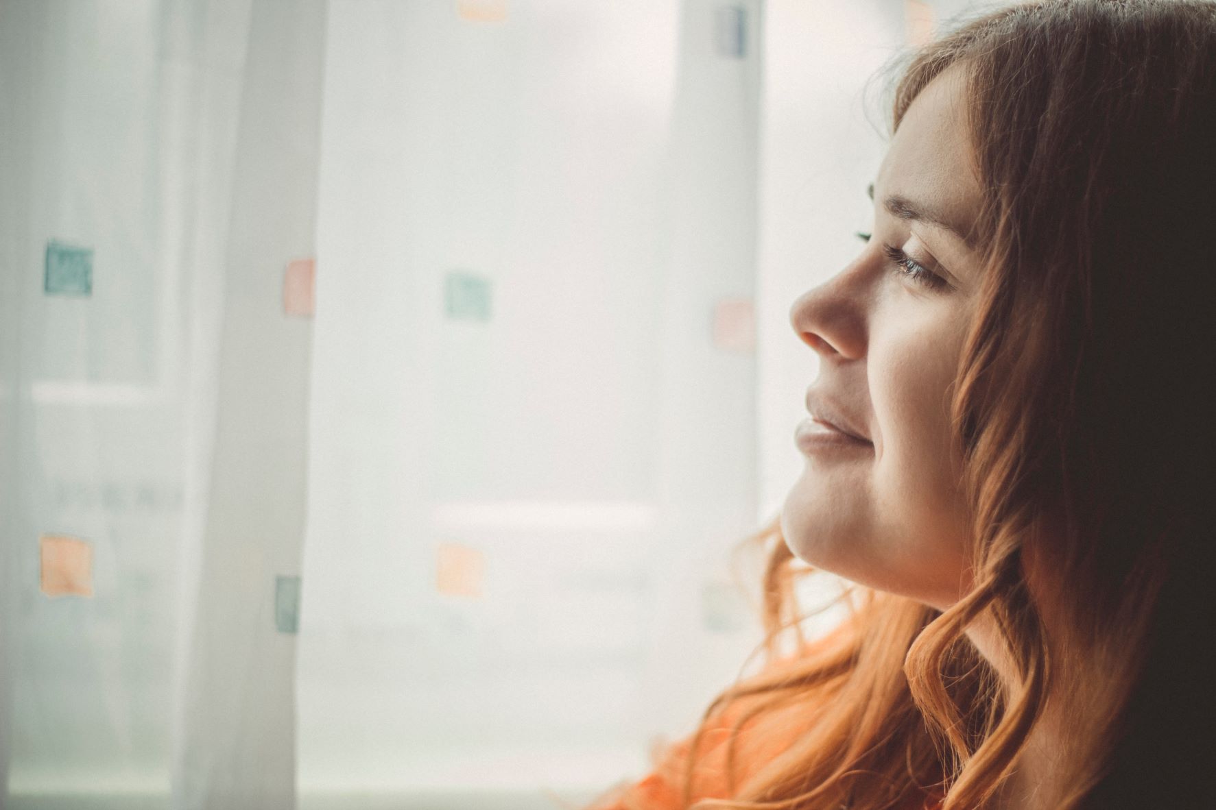 Junge Frau, die aus dem Fenster in die Ferne blickt