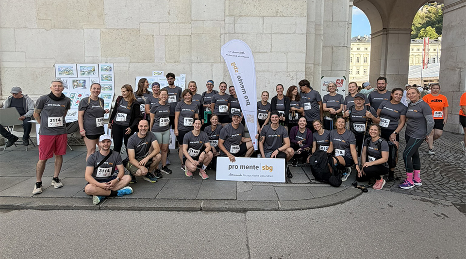 Pro mente sbg-Teilnehmer posieren für ein Gruppenfoto vor einem Torbogen in Salzburg.
